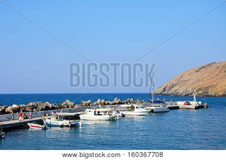 PANORMOS, CRETE - SEPTEMBER 15, 2016 - Traditional Greek fishing boats moored in the harbour with tourists walking along the quayside Panormos Crete Greece Europe, September 15, 2016.