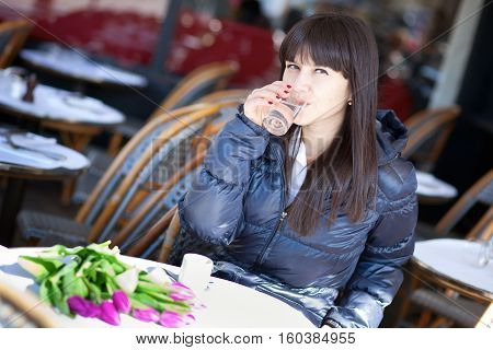 Beautiful Brunette Lady Drinking Water And Coffee In Parisian Street Cafe