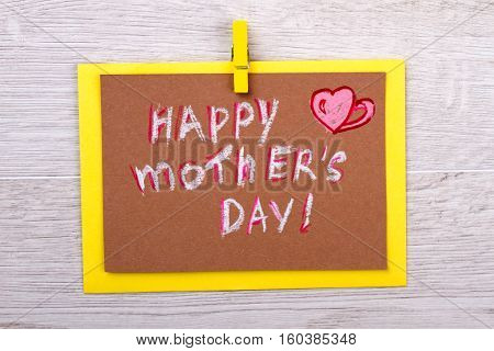 Congratulation card on Mother's Day. Greeting card on wooden background. Mom will be happy. Happy celebration of holiday.