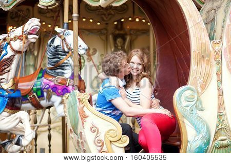 Happy Young Couple Kissing In An Equipage Of Vintage Parisian Merry-go-round