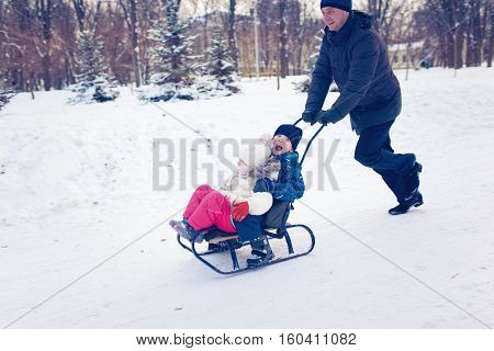 Young Family Running Through Snow With Sled