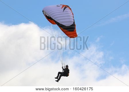 Paraglider under his wing in a blue sky