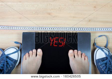 Digital scales with female feet on them and sign