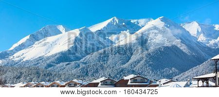 Winter travel vacation nature panoramic background with snow covered mountain peaks and snow roofs, Pirin, Bulgaria