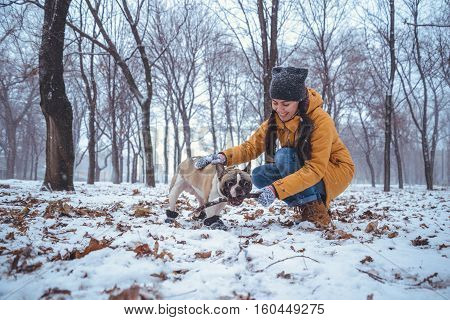 French Bulldog dog playingin the winter with woman in the park