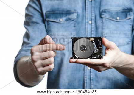 Man's hand holds a 2.5 inch hard drive. He's points to the hard disk. View of the backside HDD, from the PCB. Isolated on white background.