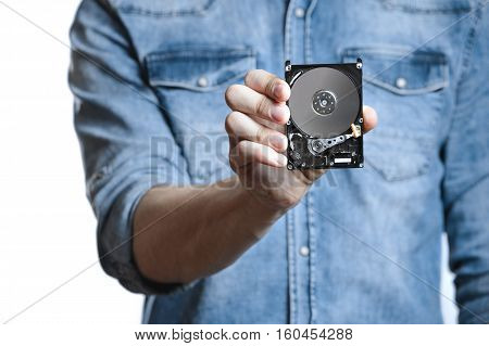 Man's hand holds a 2.5 inch hard drive. He's points to the hard disk. View of the backside HDD, from the PCB. Isolated on white background.