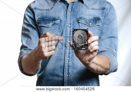 Man's hand holds a 2.5 inch hard drive. He's points to the hard disk. View of the backside HDD, from the PCB. Isolated on white background.