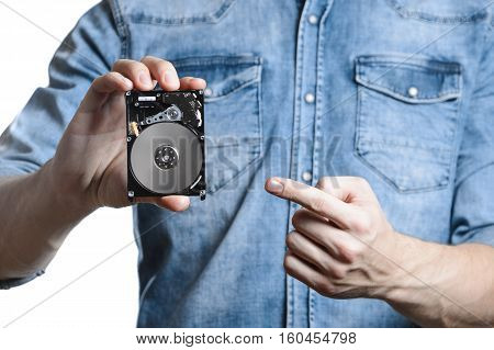 Man's hand holds a 2.5 inch hard drive. He's points to the hard disk. View of the backside HDD, from the PCB. Isolated on white background.