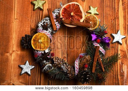 green colorful firry christmas wreath decorative with silver golden stars cone anise and cinnamon with dry orange on brown vintage wooden background