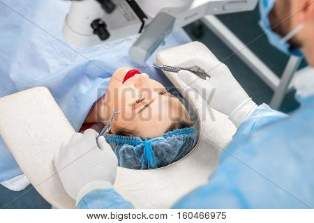 Surgion operating eye of female patient with surgical tools in the operating room