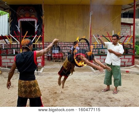 BATAM INDONESIA - DECEMBER 7 2012: Man jumping through a fire ring wearing traditional attire