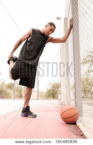 Image of young basketball player making sport exercises. Shooting at basket outdoor.