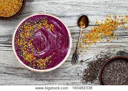 Acai breakfast superfoods smoothies bowl with chia seeds bee pollen toppings. Immune boosting anti inflammatory smoothie with turmeric honey and maca powder. Overhead top view flat lay copy space