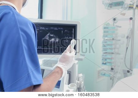 Male doctor with an ultrasound sensor in hand examining patient.
