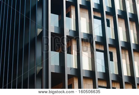 An Abstract fragment of a modern architecture facade with a black steel structure and wooden cladding.