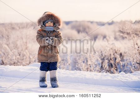 Small boy in winter snow-covered road in the cold