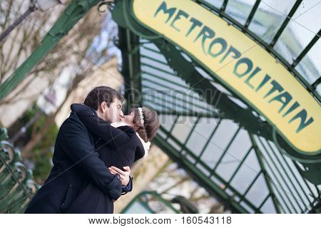 Couple Kissing Under The Metro Sign In Paris