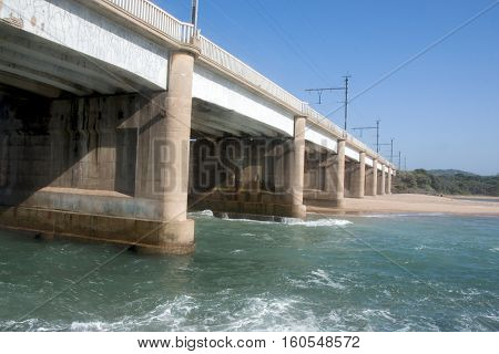 Concrete Bridge Extending Over River Mouth With Incoming Tide