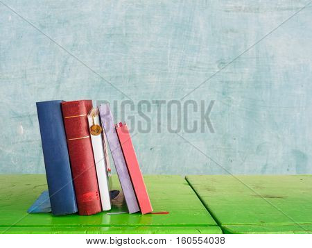 Stack of book on wooden green table with blackboard backhround and free space