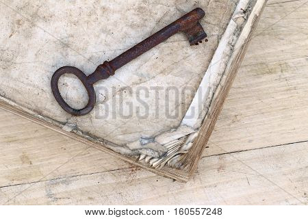 Detail of the old rusty key on the tattered book