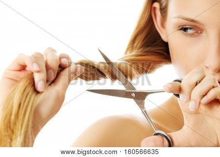 Attractive young woman is cutting her long natural hair
