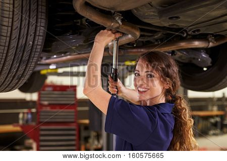 Portrait Of Female Auto Mechanic Working Underneath Car