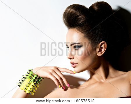 Profile portrait of a Beautiful  woman wearing bracelet with thorns and mulricolored nails