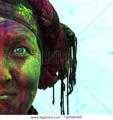 woman with blue eyes in vibrant colors on her face at Holi celebration in Rishikesh India