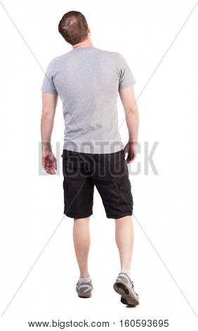 Back view of walking handsome man in shorts and sneakers.   Sports-dressed young man moves. backside view of person.  Isolated over white background. broad sporsmen in long black shorts are looking up
