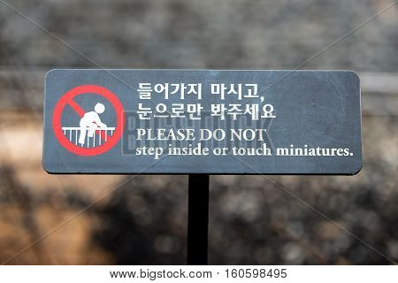 A sign in a park - Please Do Not Step inside or touch miniatures. korean(Hangul)