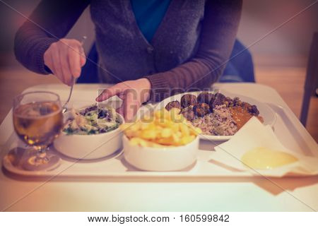 Woman in restaurant eating dinner salad with knife and fork