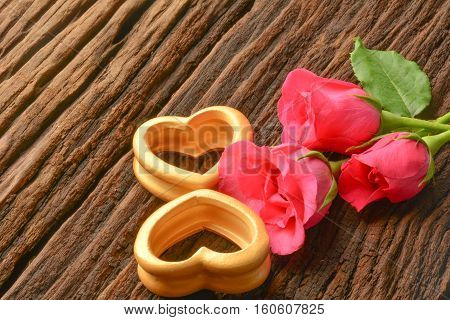 The wood hearts and three pink rose on bark.