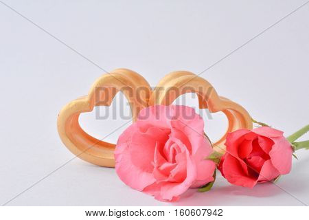 The wood hearts and two pink rose on white background.