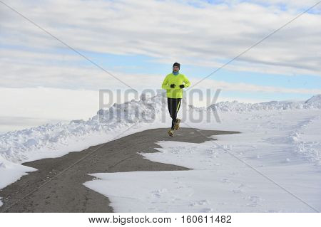 young healthy sport man running in snow mountains in trail runner hard workout in energy and endurance concept with a beautiful cold winter background