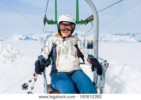 Happy female skier riding a lift. Skiing in sunny weather.