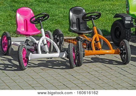 Two children's four-wheeled bicycles on pavement at the amusement park