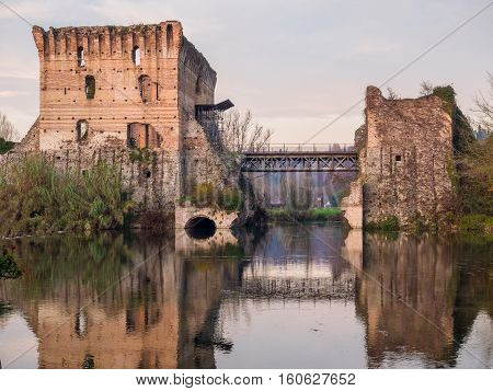 Reflections of ancient bridge in water of Mincio River at Borghetto Valeggio sul Mincio lovely town in Northern Italy.