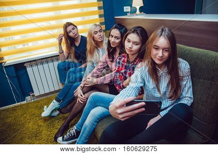 Beautiful girls sitting on the couch, have fun and make selfie in Hostel
