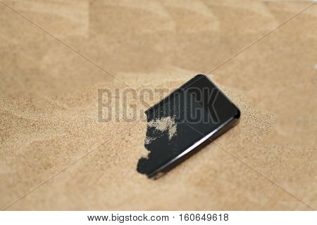 Mobile phone in sand. Isolated abstract macro photo