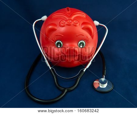 Piggy Bank and Stethoscope with Selective Focus on a blue Background.