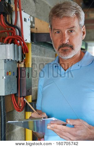 Portrait Of Electrician Standing Next To Fuseboard