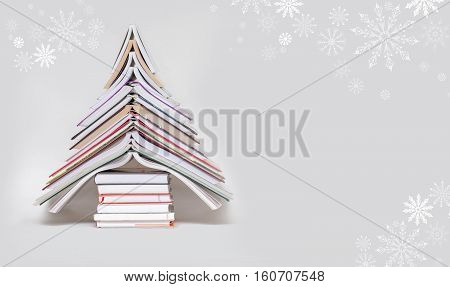 symbol Christmas tree from a colorful books on grey background. Empty copy space for your greetings
