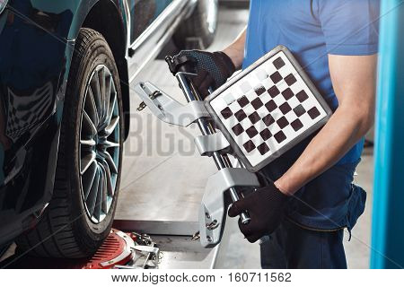 Grid sensor sets mechanic on auto. Car on stand with sensors wheels for alignment camber check in workshop of Service station