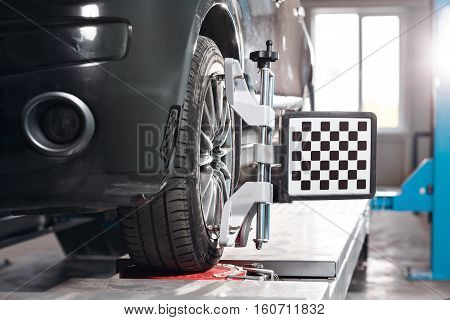 Car on stand with sensors on wheels for wheels alignment camber check in workshop of Service station.