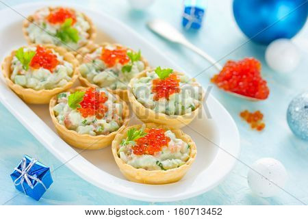 Christmas festive appetizer tartlets stuffed with salmon salad and red caviar - tasty snack for christmas or new year dinner holiday food recipe