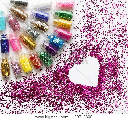 Multicolored glitter in bottles makeup place for text in heart beauty background