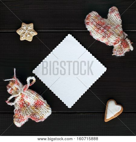 clean patterned sheet surrounded by knitted mittens and figured cookies top view / for the heart and warm greetings