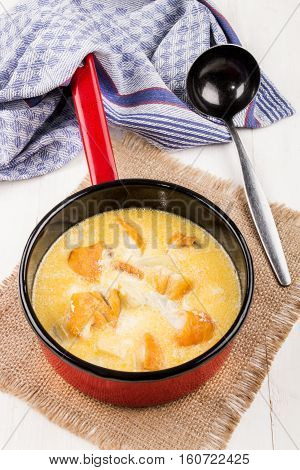freshly cooked traditional scottish fish soup cullen skink in a red enamel pot with ladle on jute