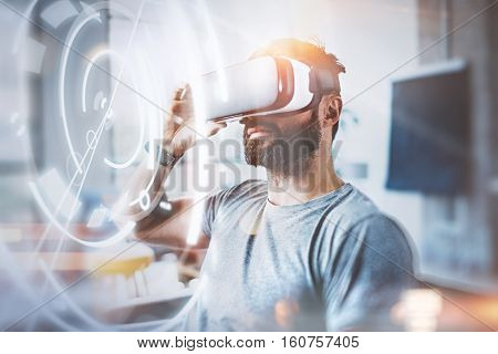 Concept of digital screen, connection and interfaces.Young beraded hipster enjoyingvirtual reality glasses in modern design loft studio.Smartphone use with VR goggles headset.Horizontal, flare, blurred